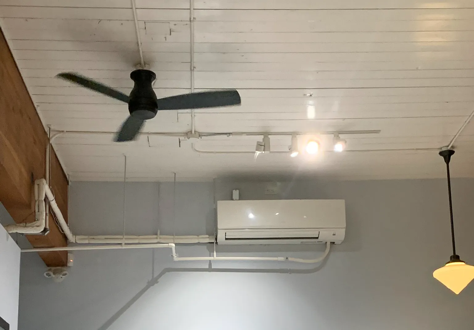 Mini-split air conditioning unit mounted on bakery interior wall with ceiling fan
