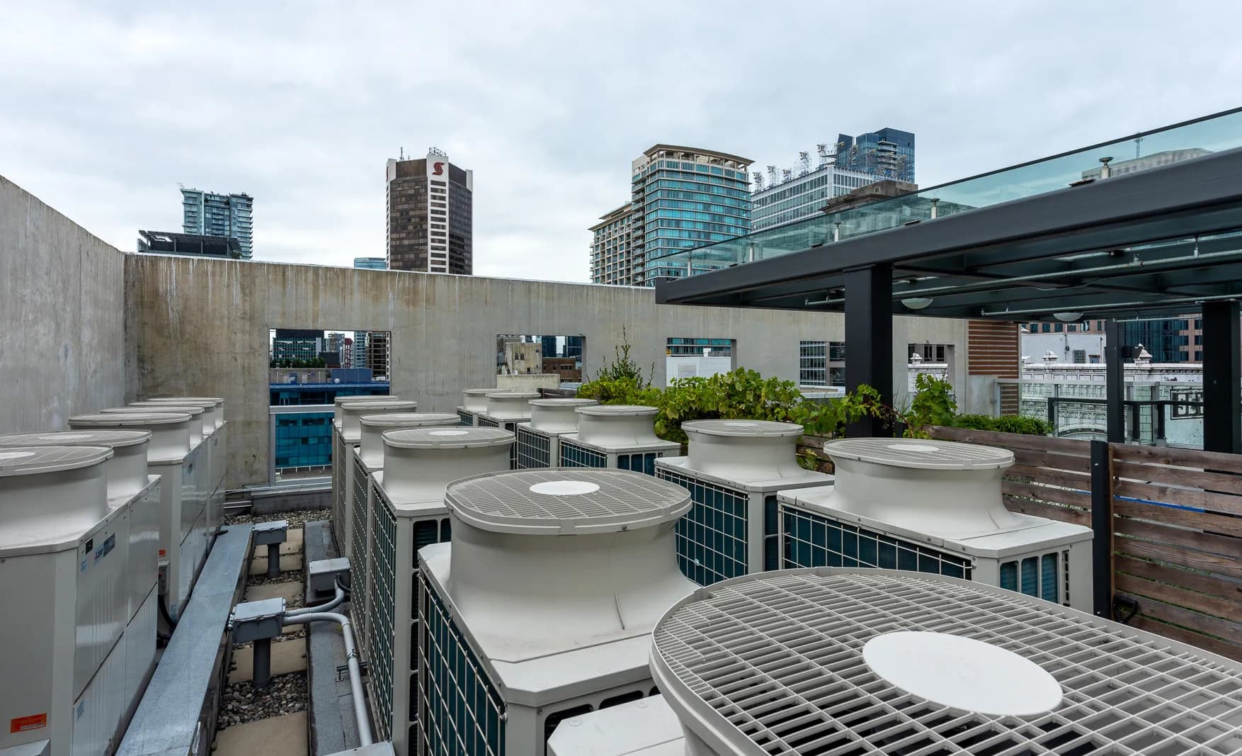 Dense array of commercial VRF HVAC rooftop units with pergola and planters on urban building